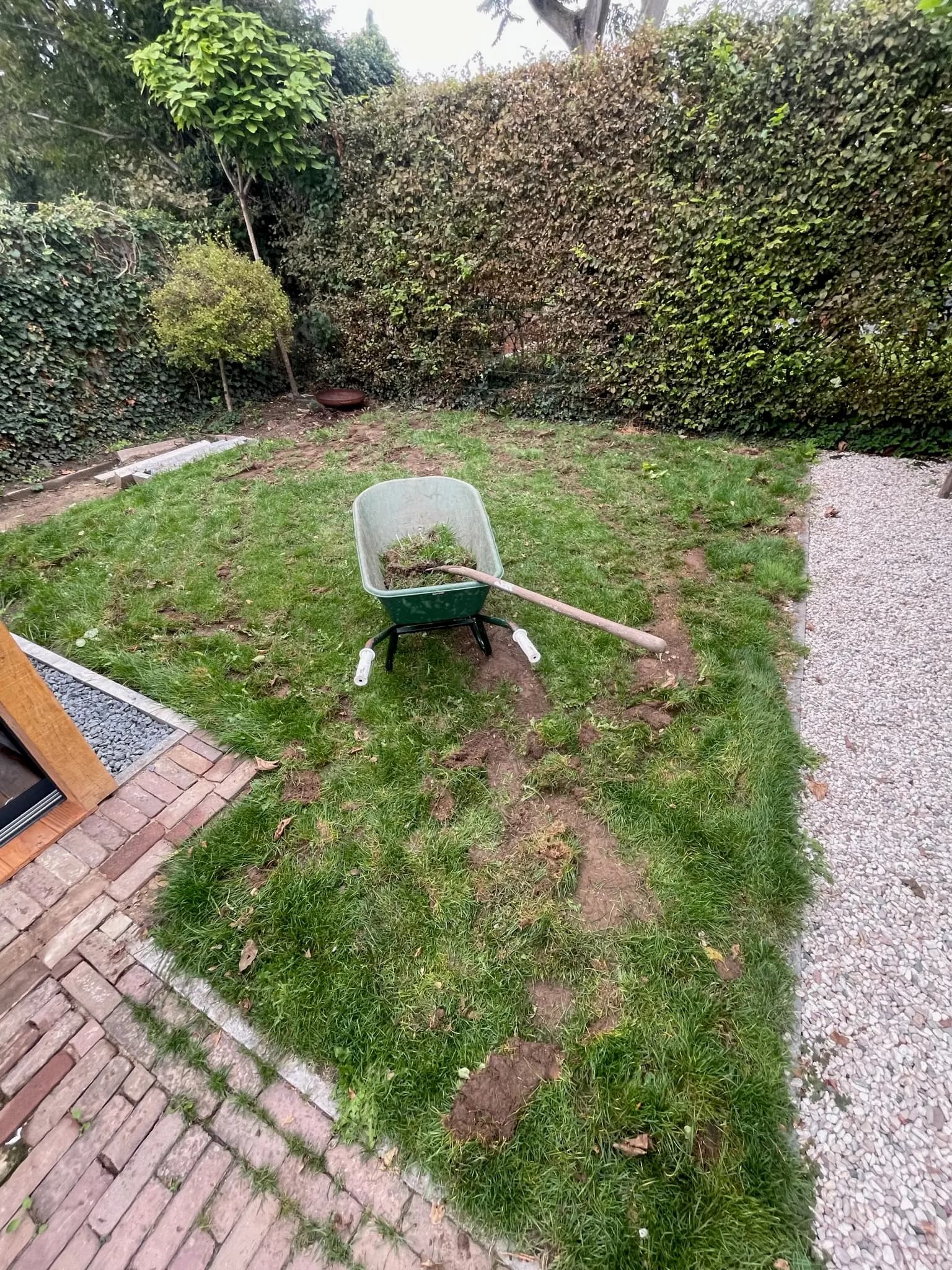 Voor: een oud gazon met kale plekken en een kruiwagen vol oude grasmat